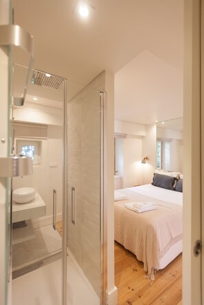 A modern bedroom with a large bed, a bedside table, and a window.