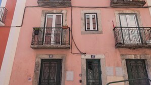 Un bâtiment rose doté de balcons, de portes numérotées et situé sur une rue pavée.