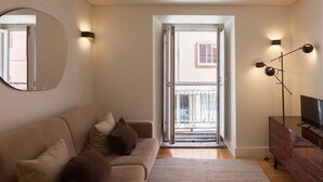 Un salon avec un canapé, un téléviseur et un miroir.