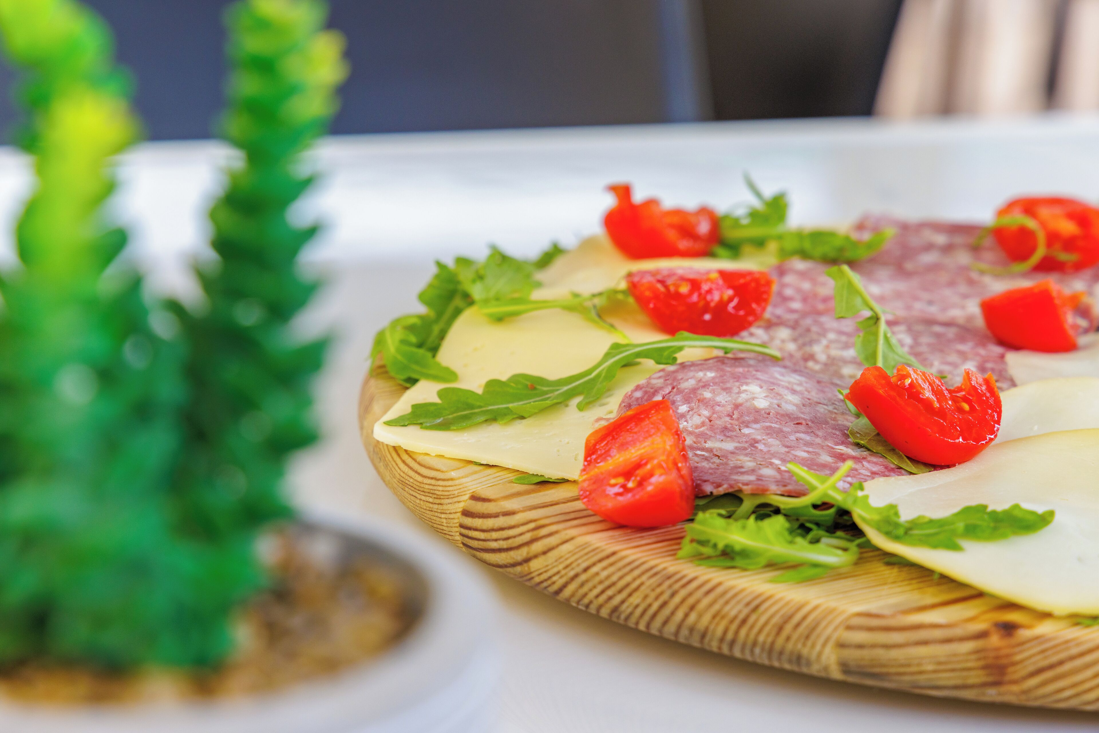 Ein Holzboden mit geschnittenem Salami, Käse und frischem Gemüse.
