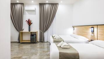 Une chambre d’hôtel avec deux lits, une tête de lit en bois, un sol en marbre, une petite table d’appoint en bois sur laquelle se trouve un vase, et un climatiseur fixé au mur.