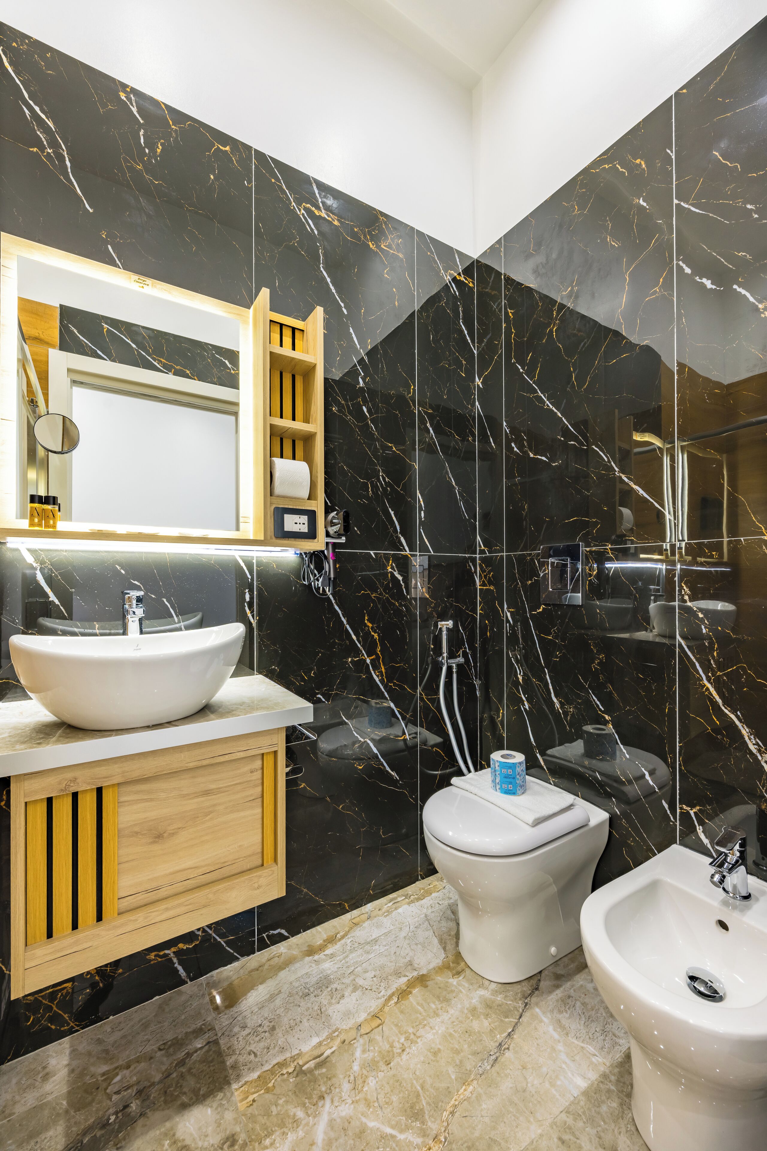 Une salle de bain moderne avec un grand miroir, un lavabo blanc, un bidet et un abattant de bidet.