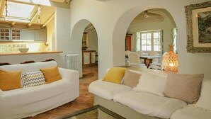 A spacious living area with white sofas, a glass coffee table, and a kitchen in the background. - FLH Belaventura Villa (Boliqueime)