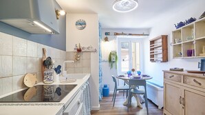 A kitchen with a stove, sink, and dining area with chairs and a table.