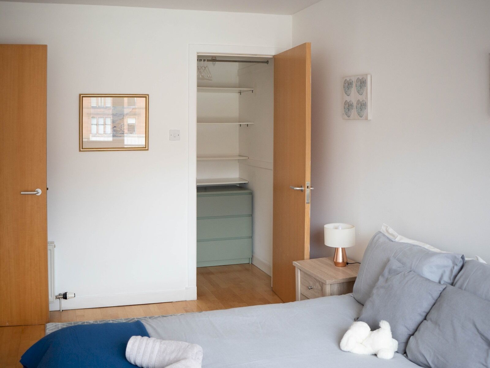A bedroom with a bed, bedside table, lamp, and a closet.