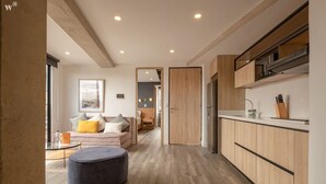 A modern kitchen with wooden cabinets and a built-in oven. There is a dining area with a round table and a sofa with cushions. - Chic 1 BR in Chapinero (Bogotá)