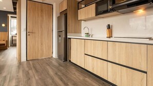 A modern kitchen with wooden cabinetry, a stainless steel refrigerator, and a microwave. - Chic 1 BR in Chapinero (Bogotá)
