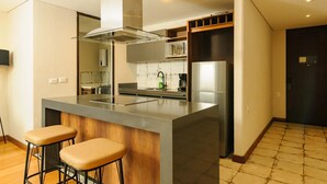 A modern kitchen with a central island, bar stools, a microwave, and a refrigerator. - Cozy 2 Br apt in Candelaria (Bogotá)