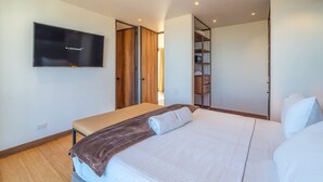 A bedroom with a bed, a bench, a TV, and a wardrobe. - Stylish 2 Masters w Patio View (Bogotá)