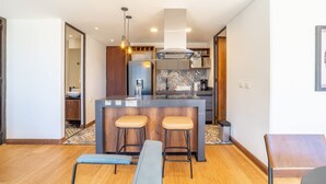 A modern kitchen with a central island, bar stools, and a dining area with a bench. - Stylish 2 Masters w Patio View (Bogotá)