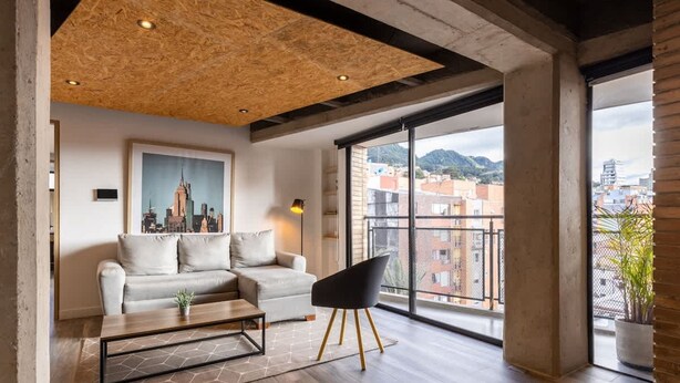 Ein modernes Wohnzimmer mit Stadtbild-Gemälde, einer Couch, einem schwarzen Sessel und einer Holzbalkendecke.