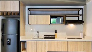 Una cocina moderna con microondas integrado, refrigerador negro y armarios de madera.