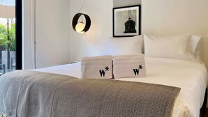 Habitación de hotel moderna con una cama grande, una lámpara colgante, un cuadro en la pared y vistas a zonas verdes.