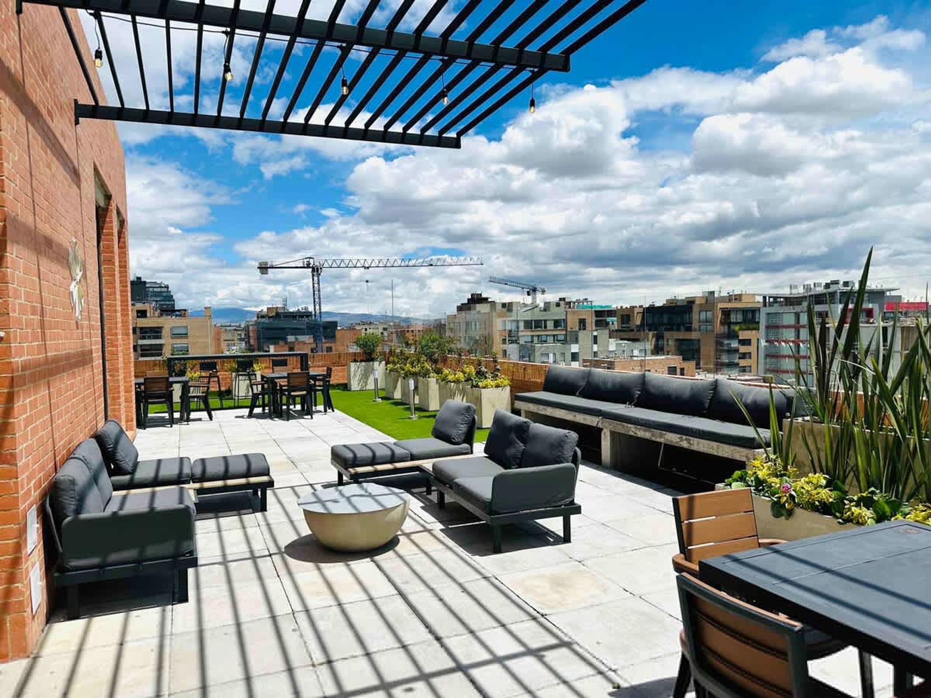 Une terrasse extérieure dotée de plusieurs espaces salon, d’un foyer et offrant une vue sur le paysage urbain.