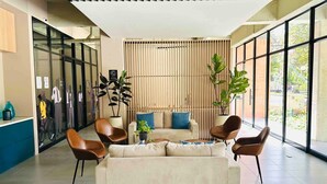 A modern lobby with a sofa, chairs, a reception desk, and large windows. - Amazing Apartment in Parque 93 (Bogotá)