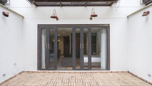 A spacious patio with a herringbone brick floor and a sliding glass door leading to an interior room. - Amazing 1 Br in Candelaria (Bogotá)