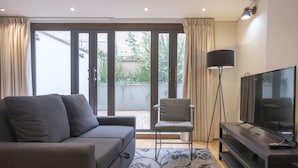 A modern living room with a sofa, a TV, and a floor lamp. - Amazing 1 Br in Candelaria (Bogotá)