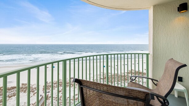 A balcony with a view of the ocean, a chair, and a small table. - Perdido Towers West 1005 (Pensacola)