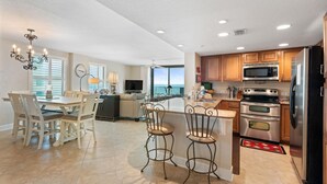 A spacious kitchen with a dining area, a large island, and a view to the outside. - Perdido Towers West 1005 (Pensacola)