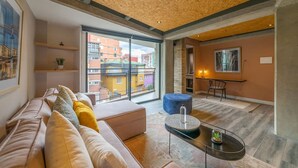 A modern living room with a wooden ceiling, large windows, a sofa, a coffee table, and a dining area. - Modern 1 BR in Chapinero (Bogotá)