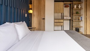 A modern bedroom with a large bed, a wooden wardrobe, and a built-in kitchen area. - Stunning 1 BR in Chapinero (Bogotá)