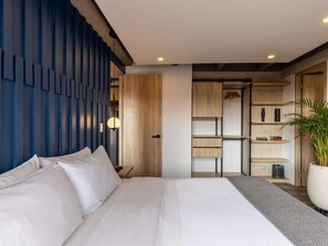 A modern bedroom with a large bed, a bedside table, a wardrobe, and a built-in shelving unit.