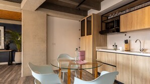 A modern kitchen with wooden cabinets, a stainless steel sink, and a glass dining table with chairs. - Classy 1 BR in Chapinero (Bogotá)