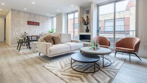 Un salon moderne comprenant un canapé, deux fauteuils, une table basse et un coin repas avec une table et des chaises.