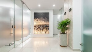 A modern reception area with a glass partition, a large abstract painting, and a potted plant. - Modern 3BR in Usaqu n (Bogotá)