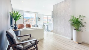 A modern living room with a sofa, chairs, a dining table, and a large potted plant.