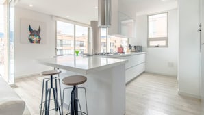 A modern kitchen with a large island, bar stools, and a stainless steel range hood.