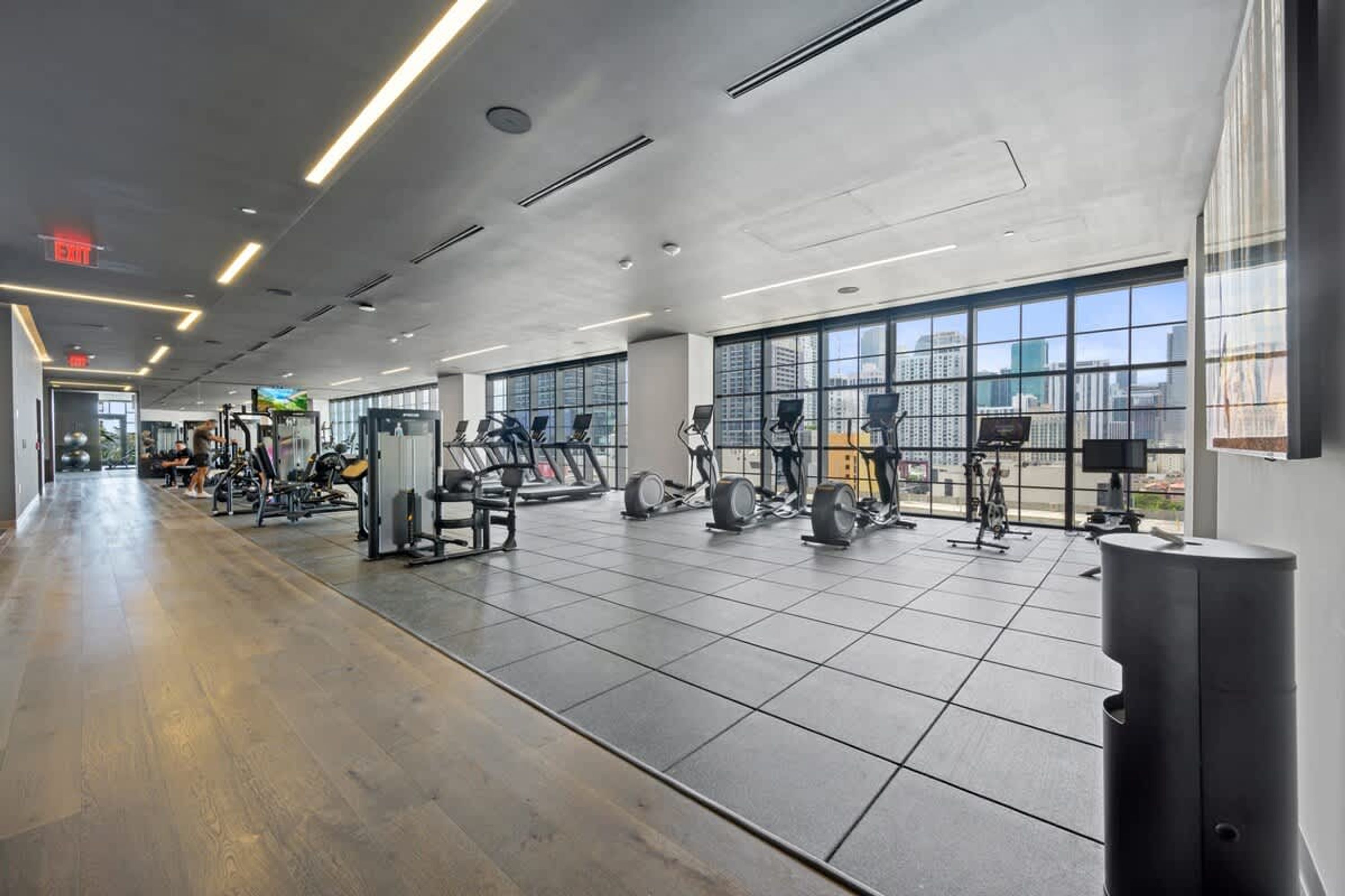 Una palestra moderna con diverse attrezzature per l'allenamento, ampie finestre e un ambiente pulito e spazioso.
