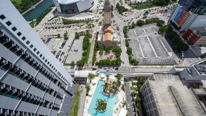 Un hotel de gran altura con piscina en la azotea, un estadio grande y una calle urbana con mucho tráfico.