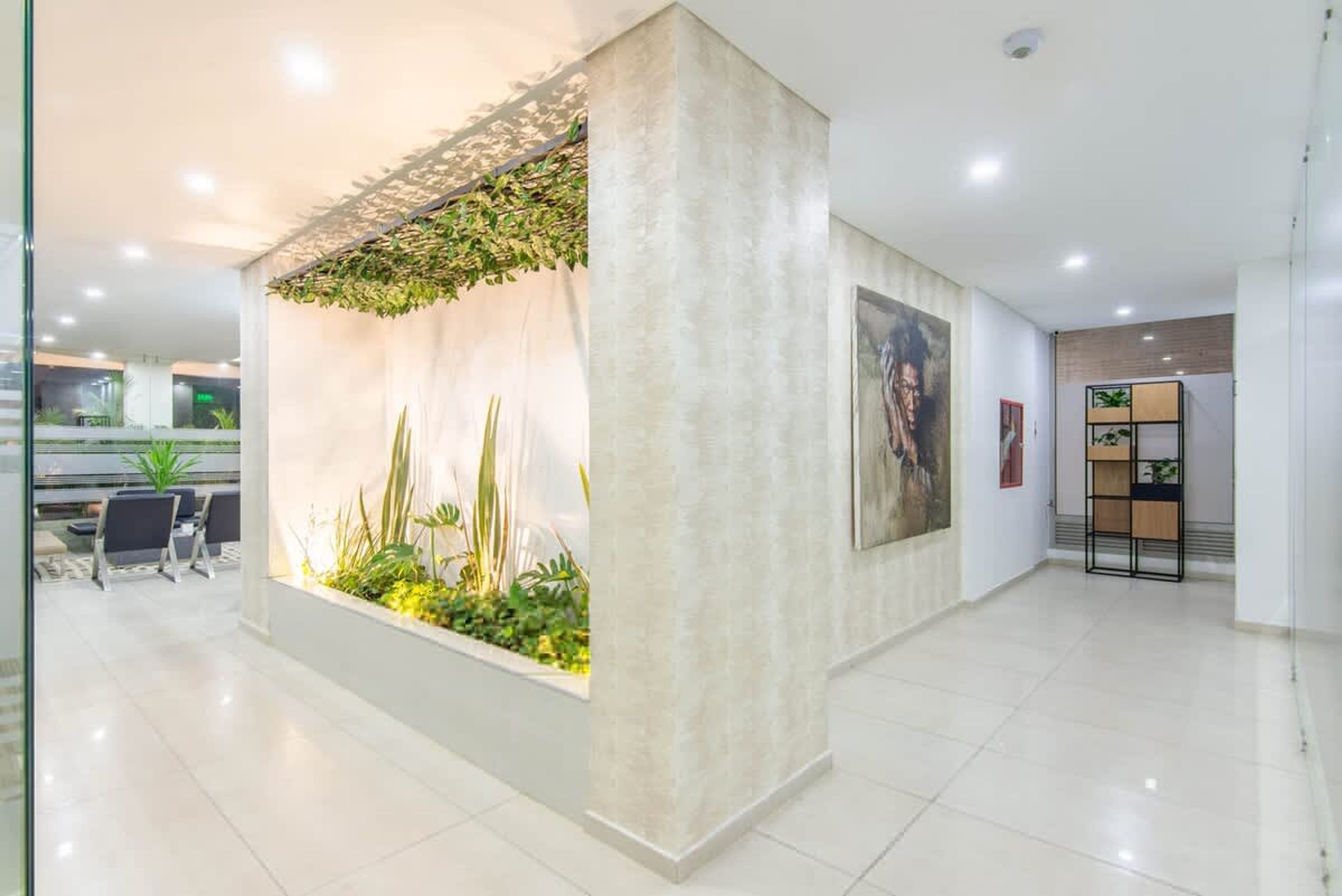 A modern reception area with a plant wall, seating, and a framed artwork on the wall.