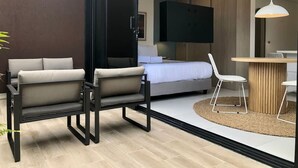 Une chambre d’hôtel moderne, équipée d’un lit, d’un bureau et de deux chaises.