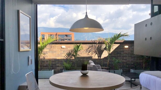 Un intérieur moderne avec une table ronde en bois, des chaises blanches et un luminaire suspendu.