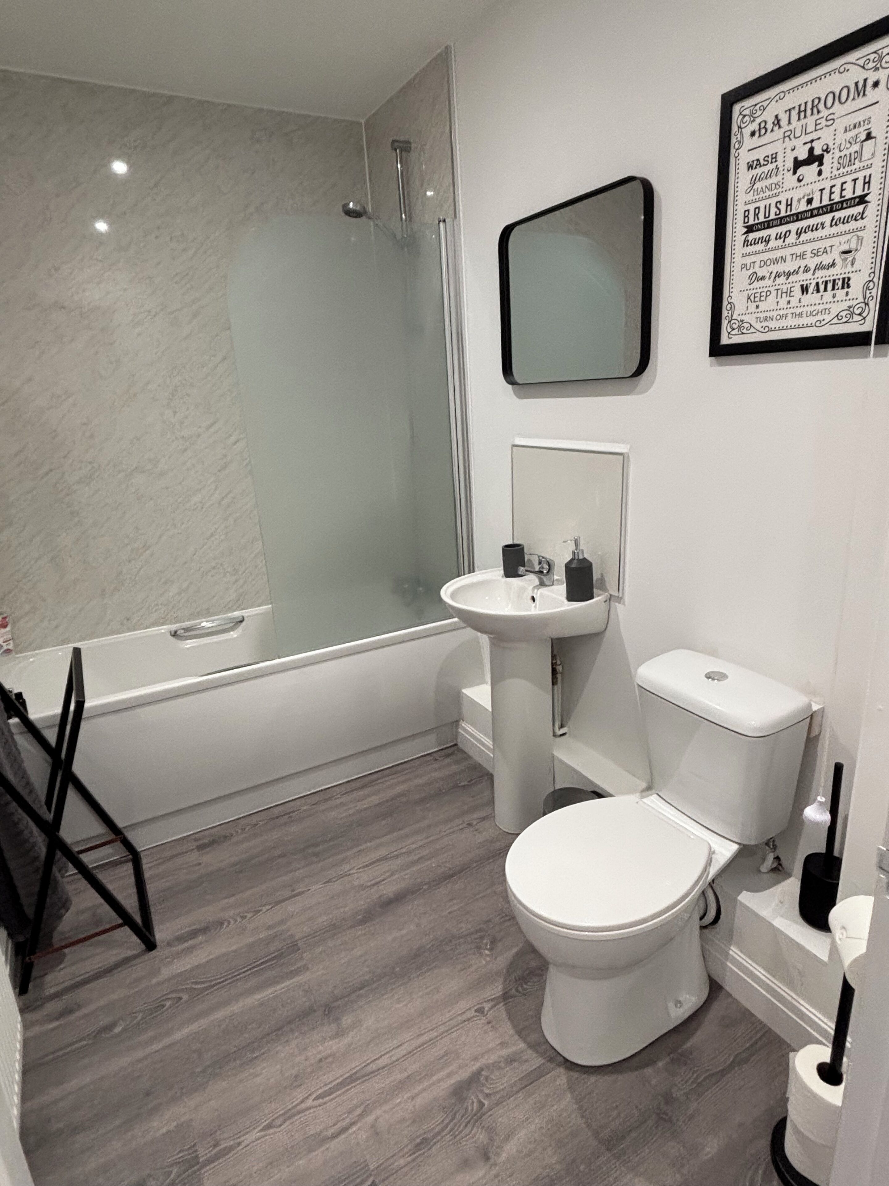 Een moderne badkamer met een douchecabine van glas, een wit wastafelmeubel en een toilet.