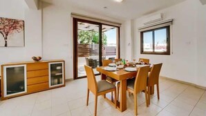 A dining area with a wooden table and chairs, a cabinet with glass doors, and a sliding glass door leading to an outdoor area. - Villa Marianna in Cape Greko with heated pool (Cape Greko)