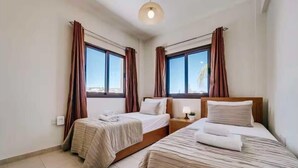 A hotel room with two beds, a nightstand with a lamp, and a window with curtains. - Villa Marianna in Cape Greko with heated pool (Cape Greko)