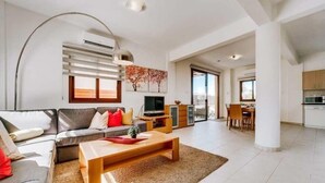 A modern living room with a sofa, coffee table, TV, and artwork. - Villa Marianna in Cape Greko with heated pool (Cape Greko)