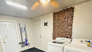 Une buanderie équipée d’un ventilateur de plafond, de deux machines à laver, d’une serpillière, d’un balai et d’une porte.
