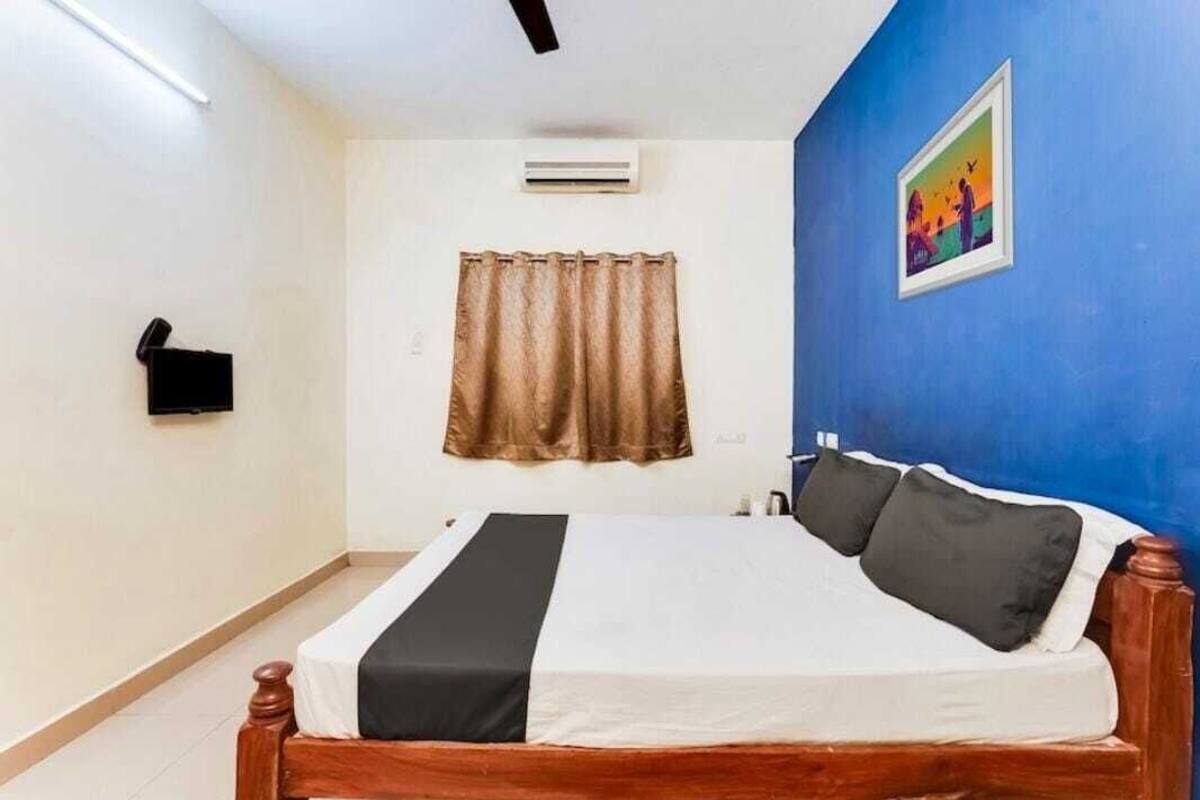 Un dormitorio con una cama de madera, una cortina marrón, un aire acondicionado instalado en la pared y un cuadro en la pared azul.