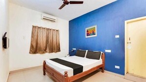 Ein Schlafzimmer mit einem hölzernen Bett, einem Deckenventilator, einer blauen Wand und einer Tür.