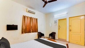 Ein Schlafzimmer mit einem Bett, zwei Stühlen, einem Deckenventilator, einer Klimaanlage und zwei Türen.
