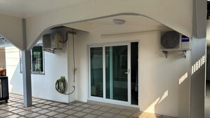 A covered outdoor area with a tiled floor, a sliding glass door, and two air conditioning units mounted on the wall.