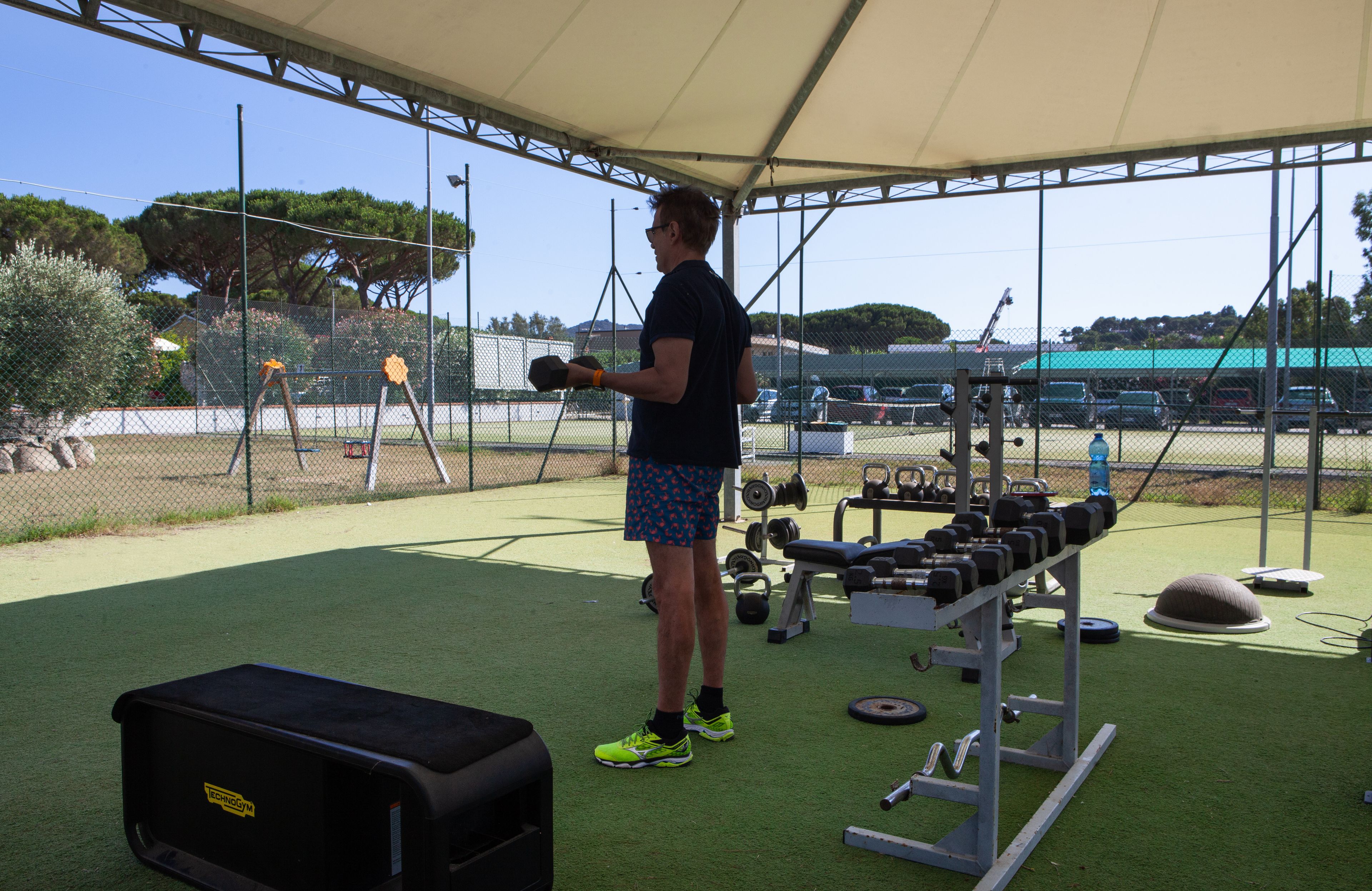 A covered outdoor gym area with exercise equipment and a weight bench.