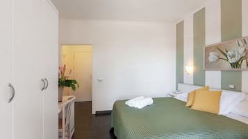 A hotel room with a bed, a bedside table, a mirror, and a wardrobe.