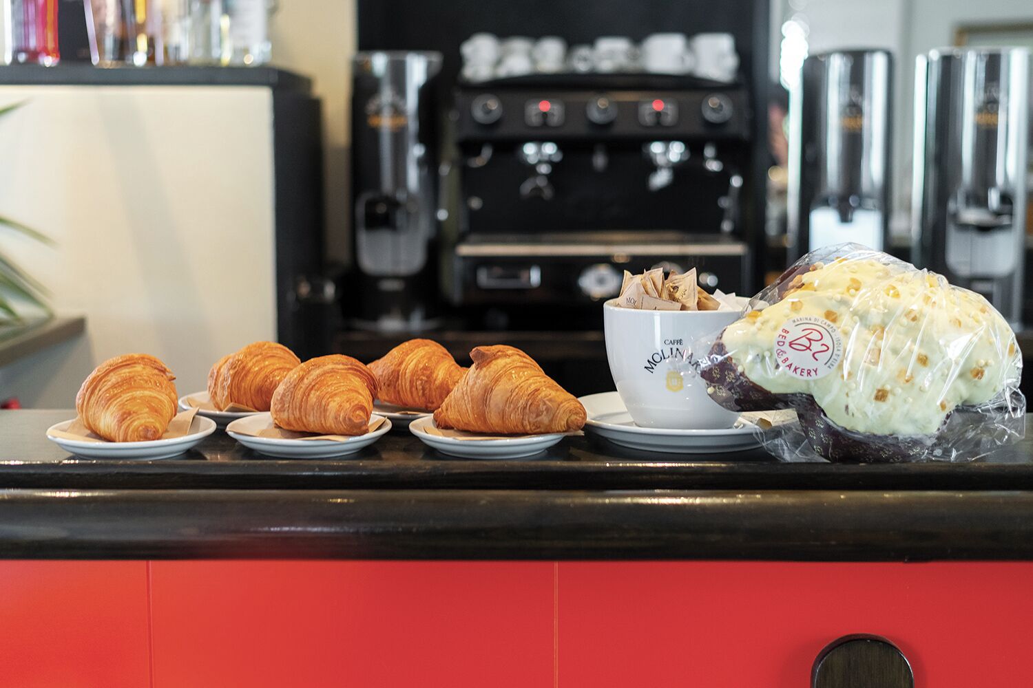 Croissants on plates and a bowl of coffee on a counter.