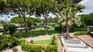Un jardín ajardinado con zonas de estar, árboles y un camino pavimentado.