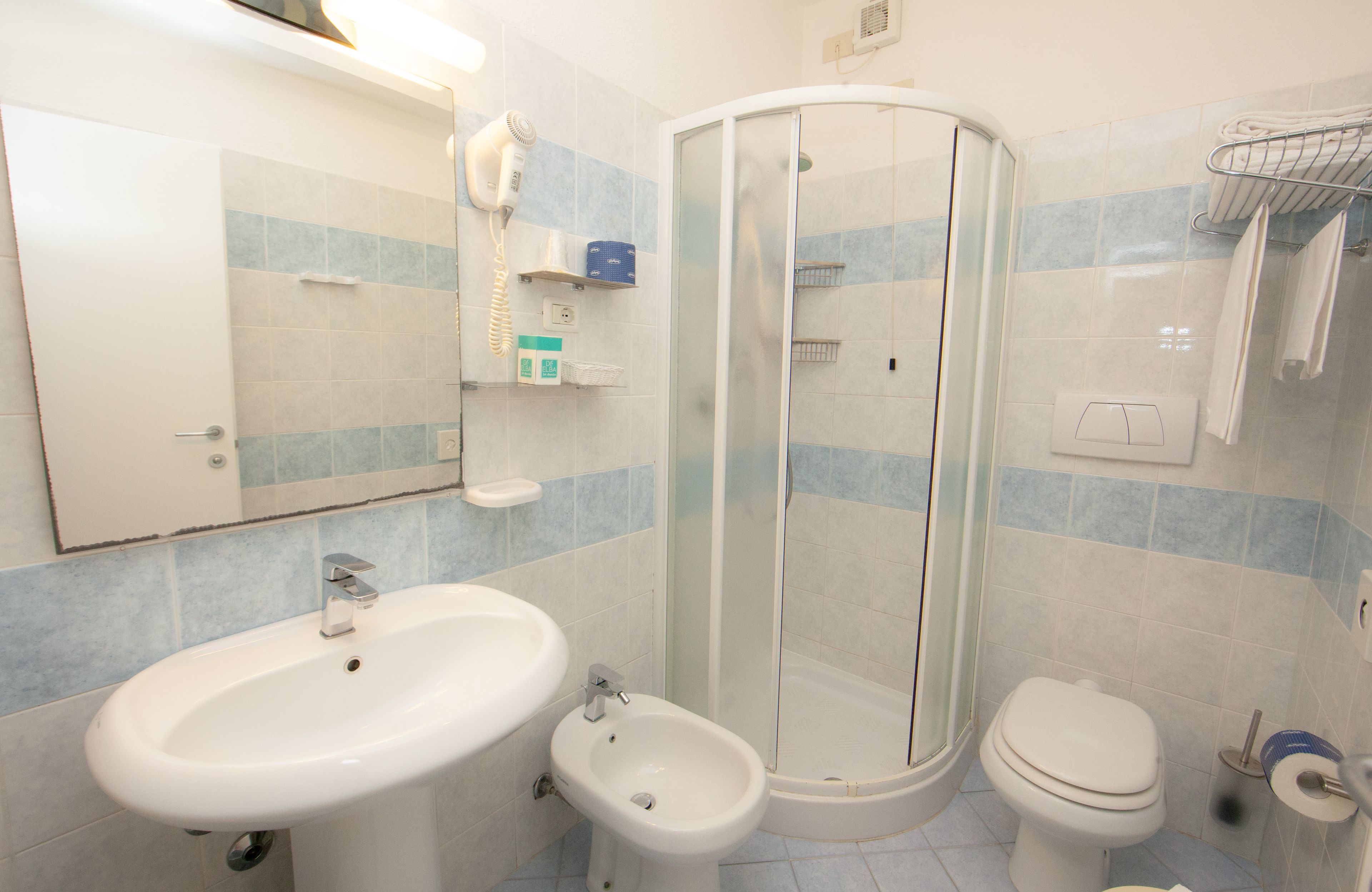 A bathroom with a sink, bidet, toilet, and a glass-enclosed shower.